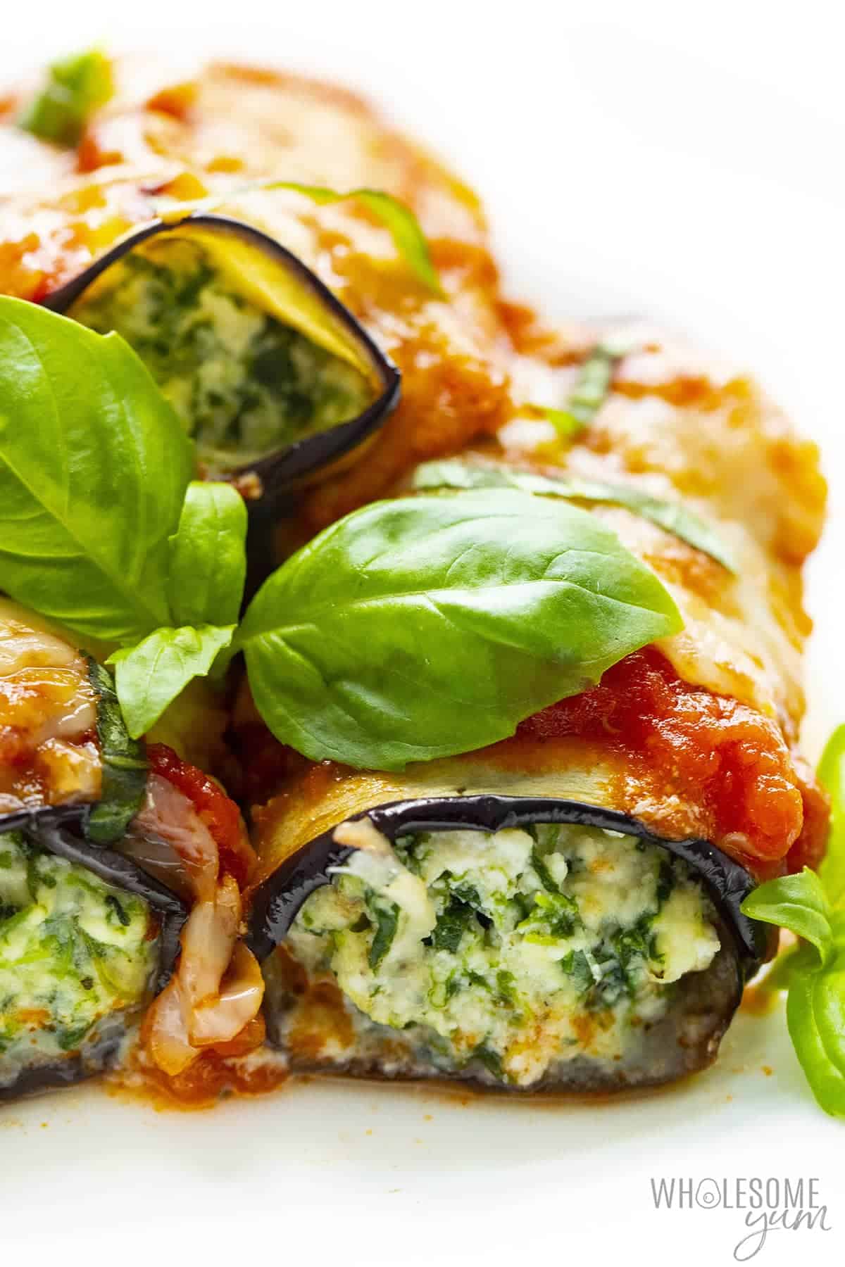 Eggplant rollatini recipe stacked together, with fresh basil.