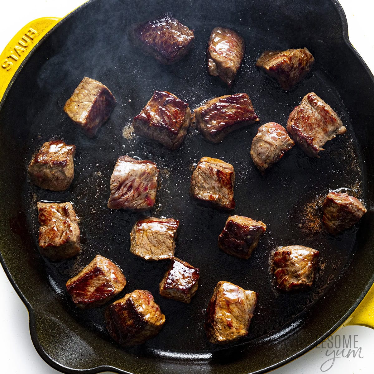 Steak bites seared on all sides in a cast iron skillet.
