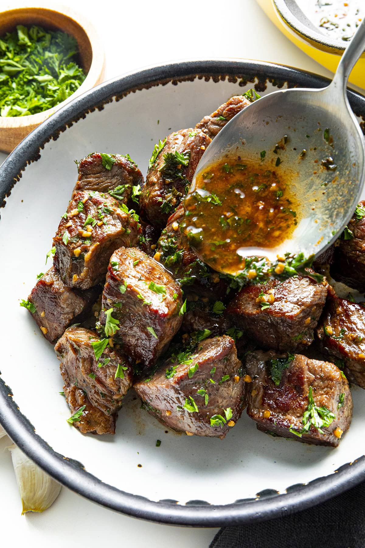 Steak bites in a bowl drizzled with garlic butter sauce.