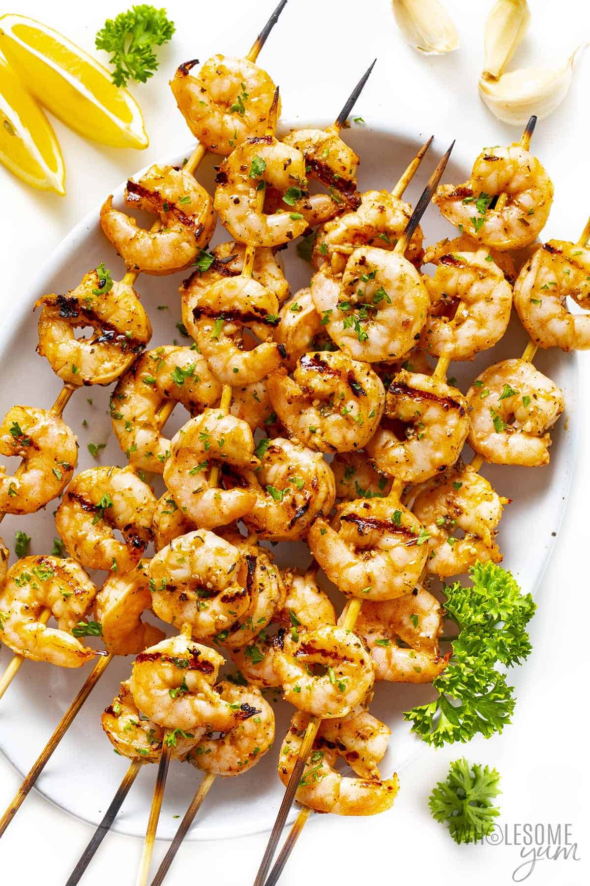 Finished shrimp skewers recipe on a plate with fresh lemon and herbs