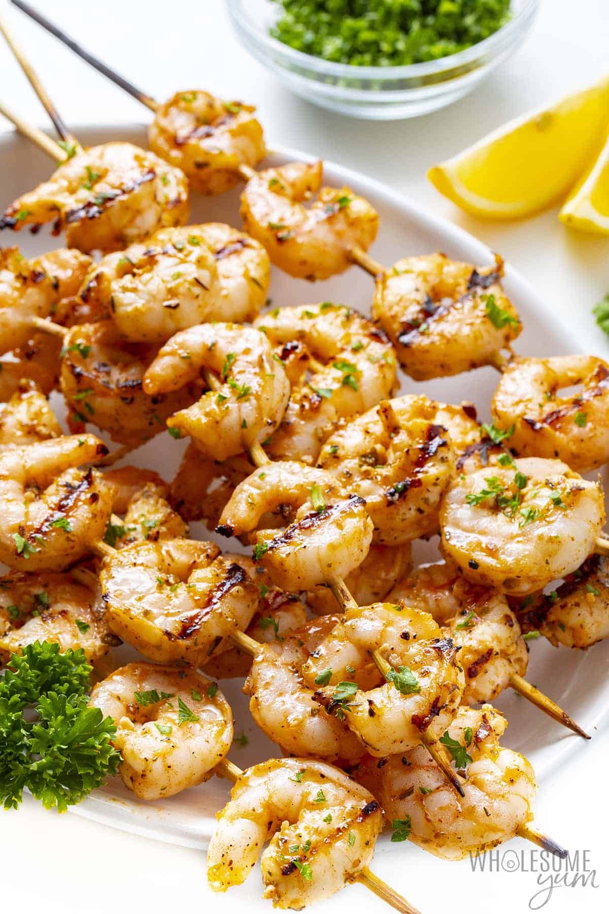 Cooked garlic shrimp skewers displayed on a plate with lemon wedges