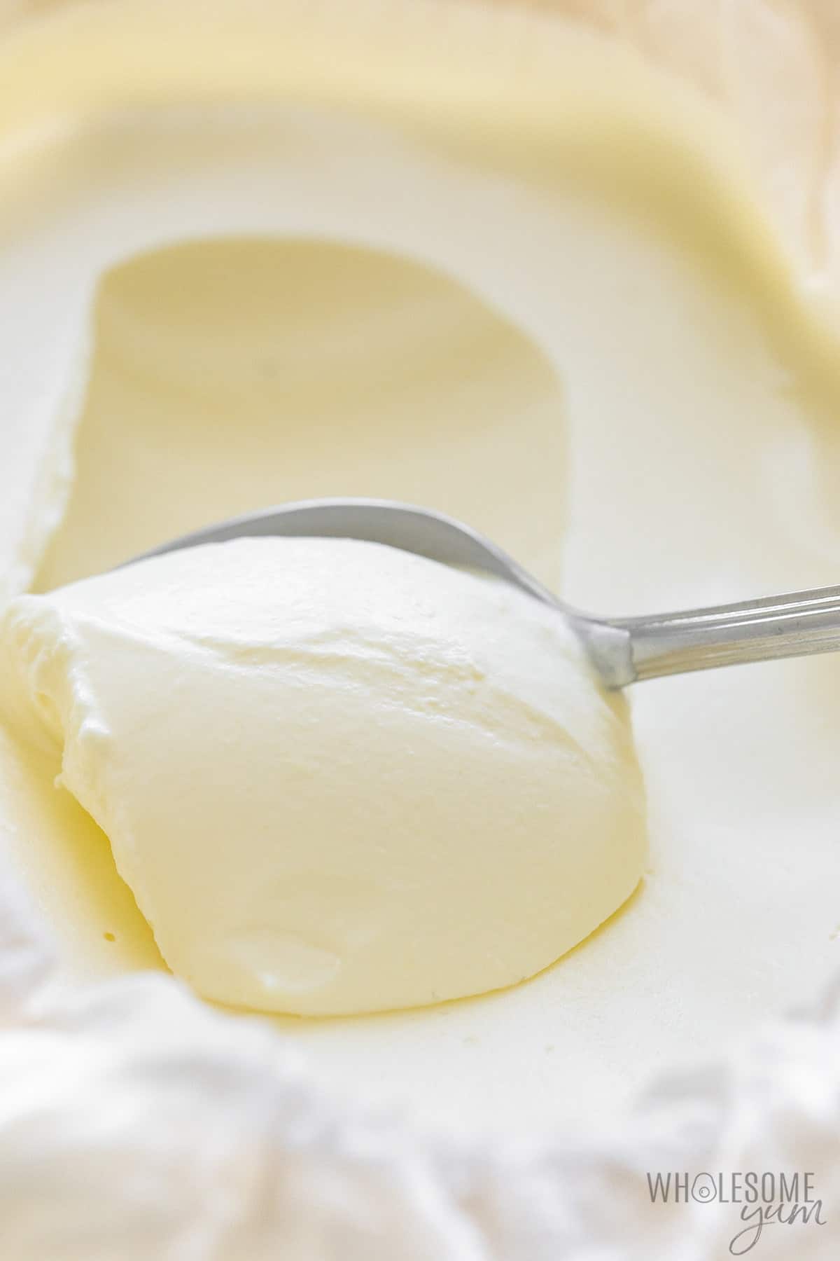 Spoon scooping mascarpone cheese in a bowl