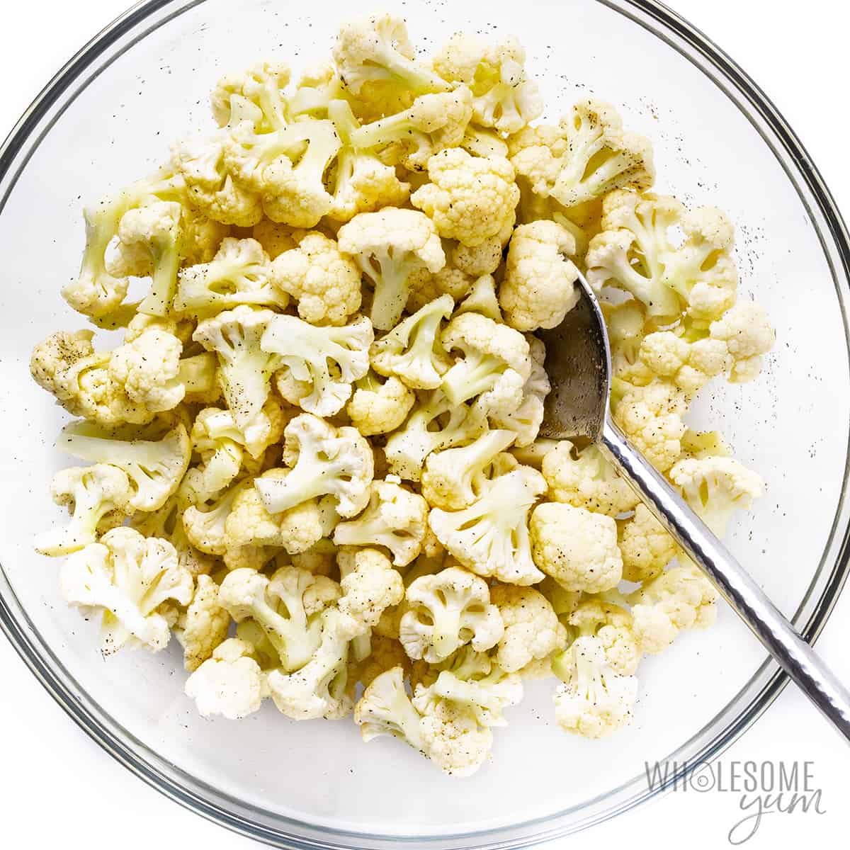 Cauliflower florets with oil and seasonings in a bowl.