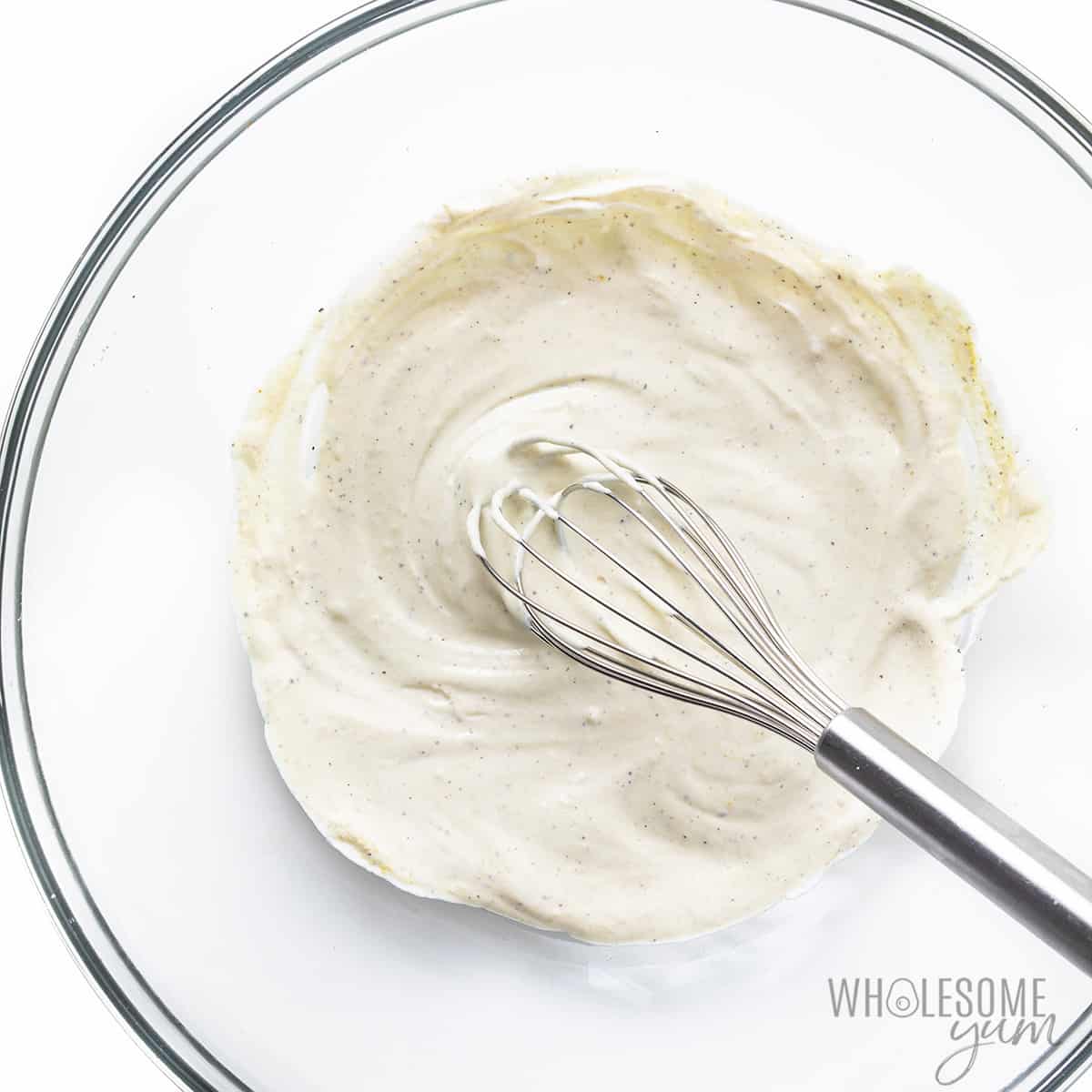 Dressing ingredients mixed in a bowl with whisk.