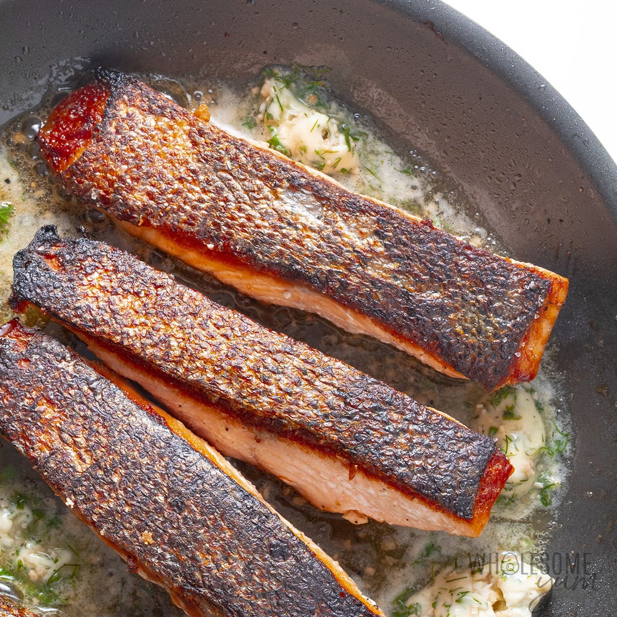 Pan seared salmon in skillet, skin side up.