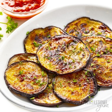 Sauteed eggplant recipe on a plate with marinara in background