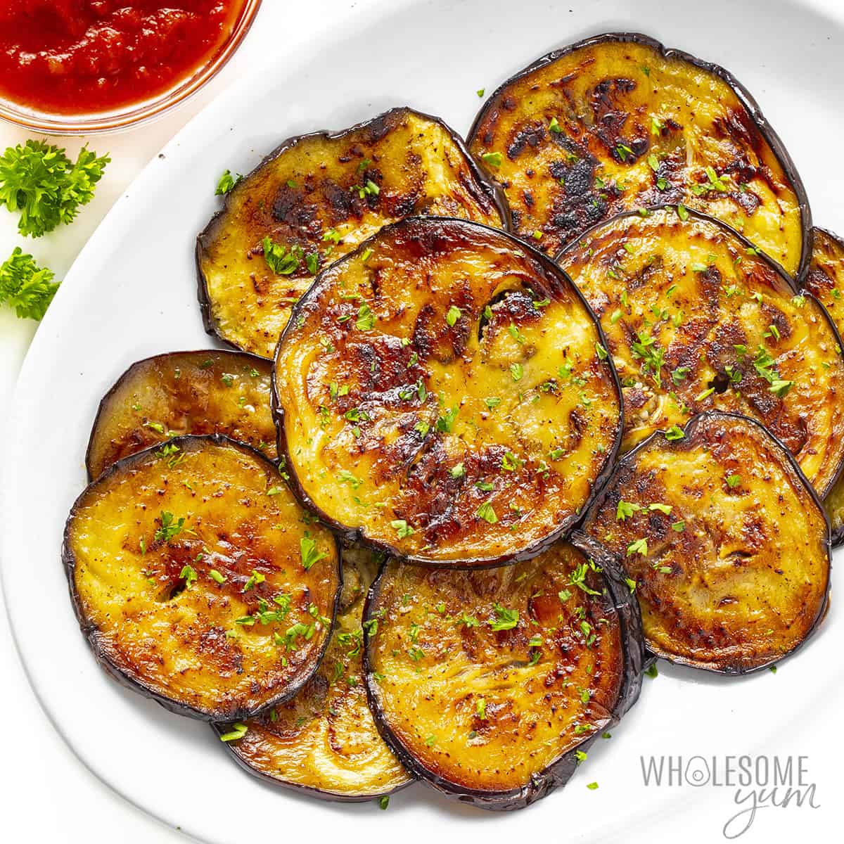 Cooked eggplant recipe with fresh herbs for garnish.