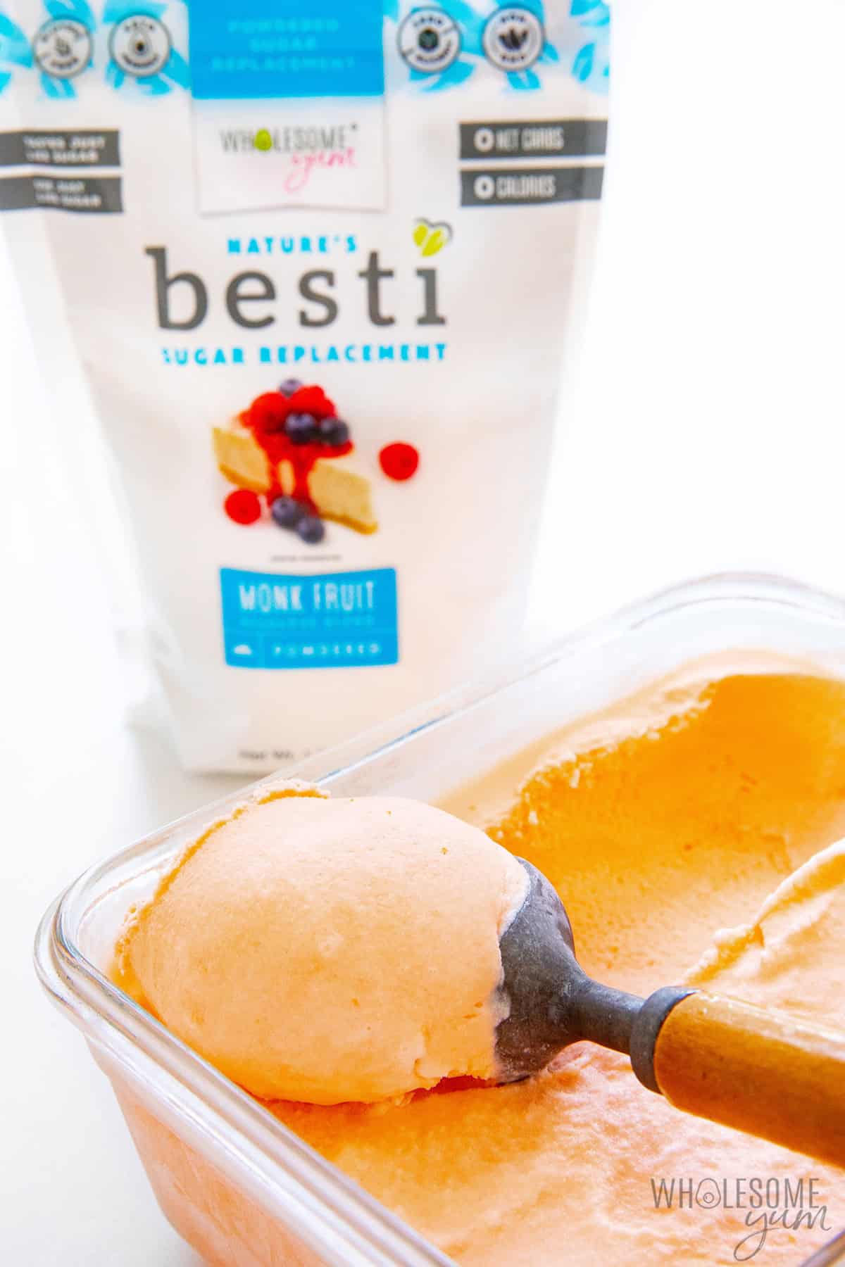 Scooping creamy sugar free sherbet with an ice cream scoop and Besti in the background.