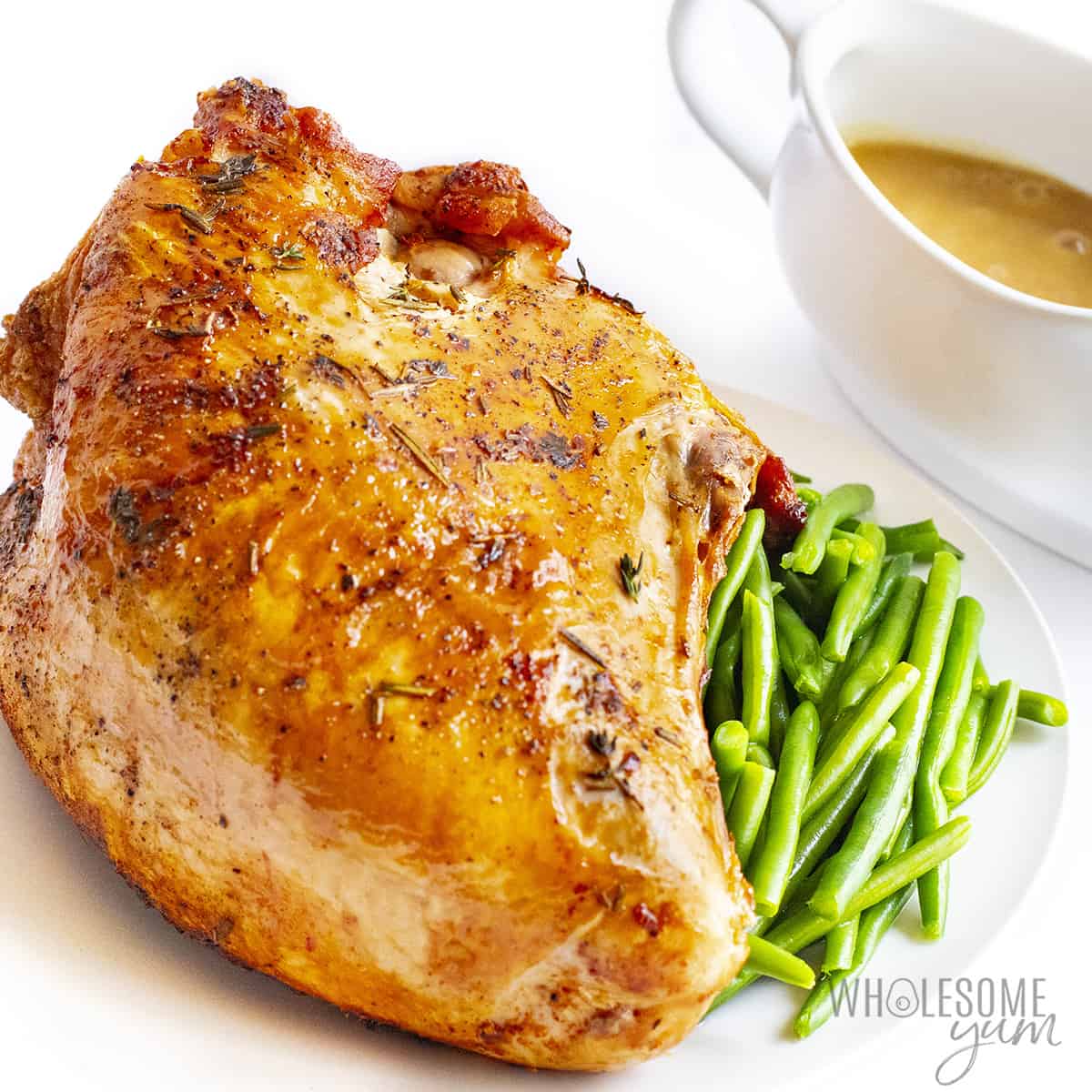 Air fryer turkey breast resting on a platter with green beans.