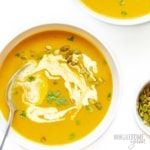 Bowl of pumpkin soup with garnishes and spoon