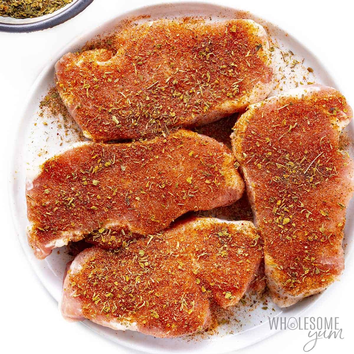 Pork chops with dry rub on a plate.