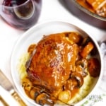 Coq au vin on a plate with glass of wine