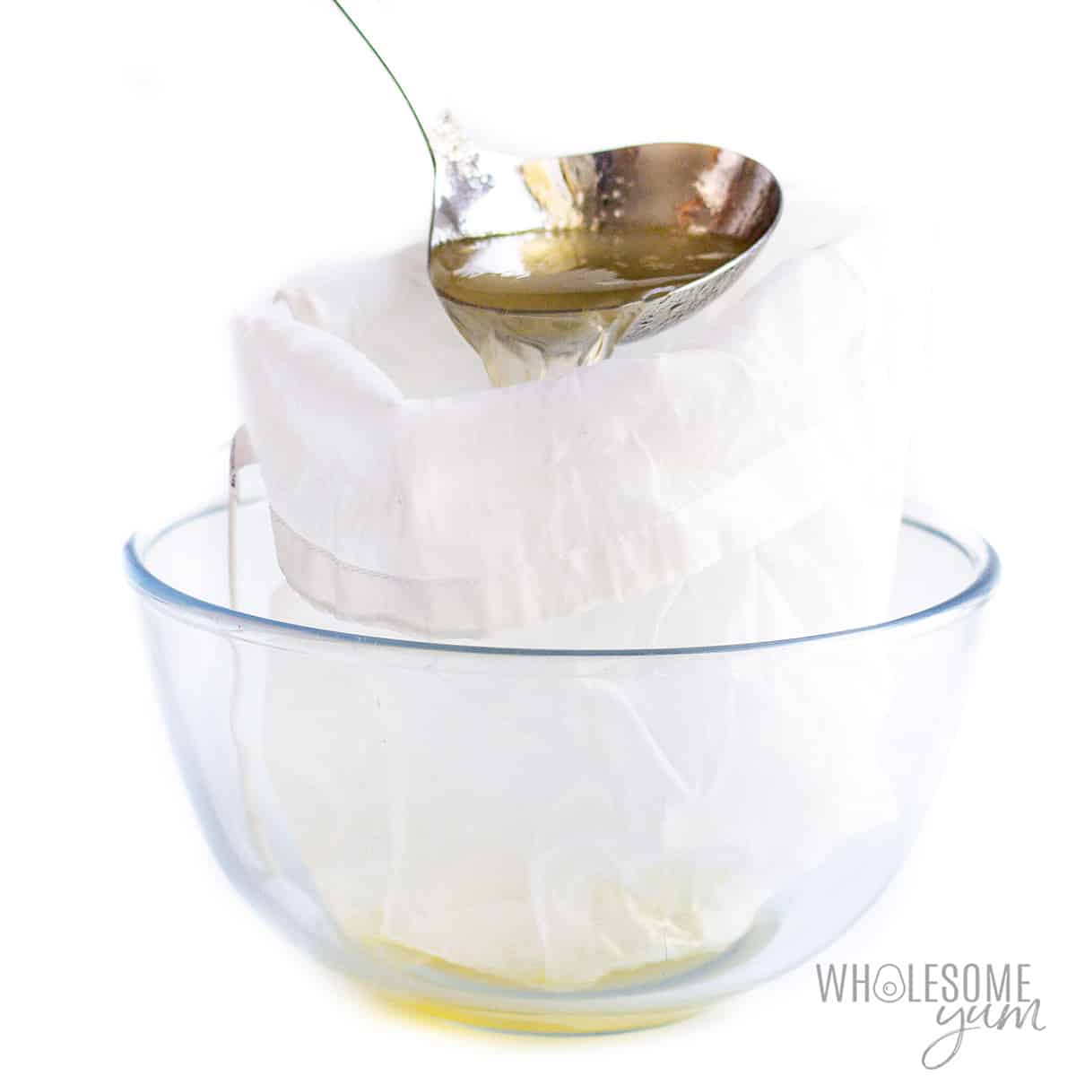 Straining in a nut milk bag over glass bowl.