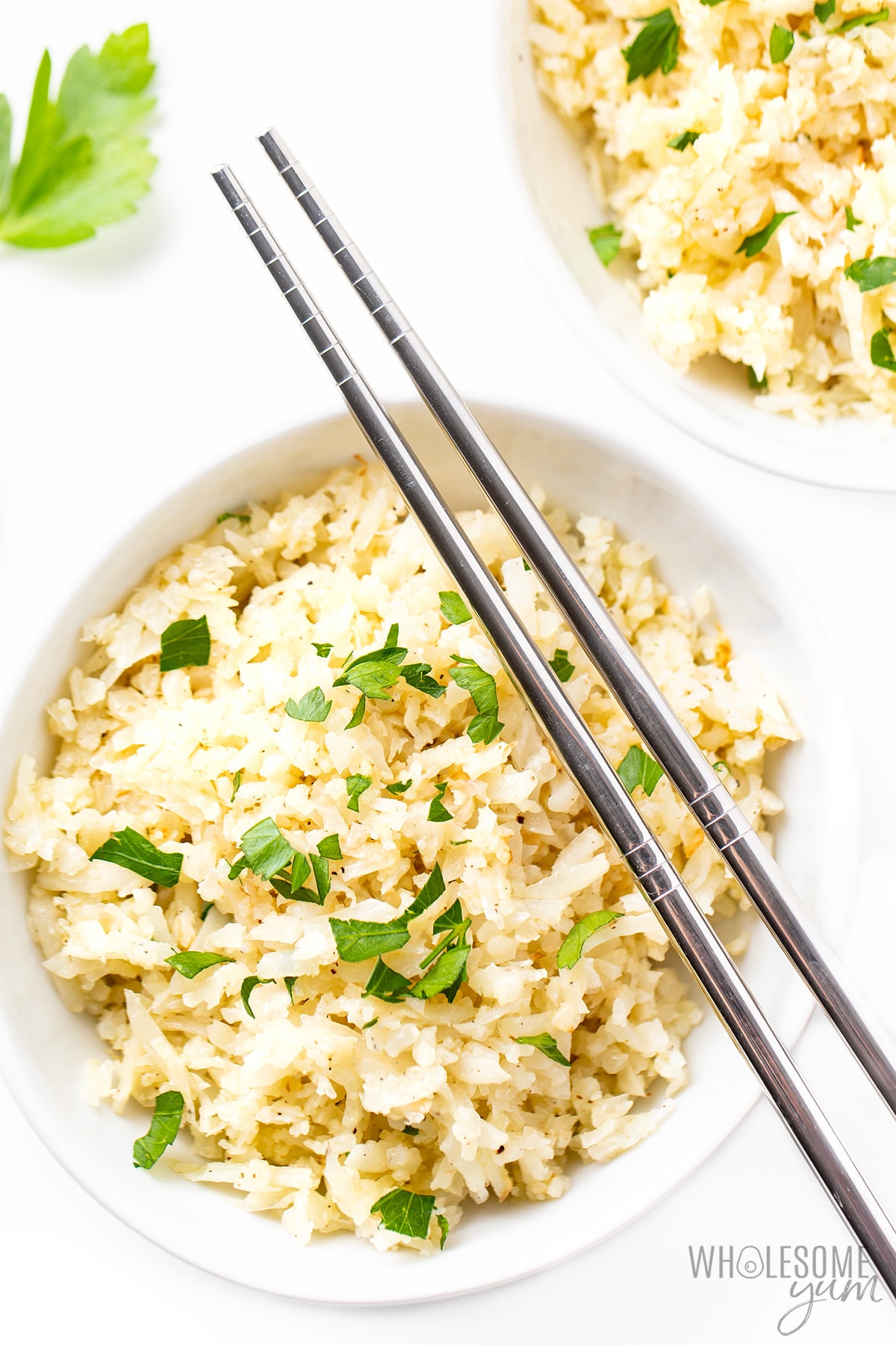 Riced cauliflower in two bowls with chopsticks.