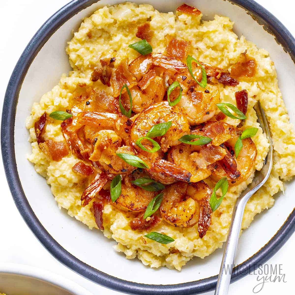 Shrimp and cauliflower grits recipe in a bowl with a fork