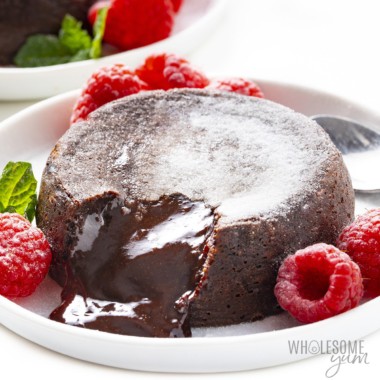 Keto chocolate lava cake overflowing on a plate with raspberries