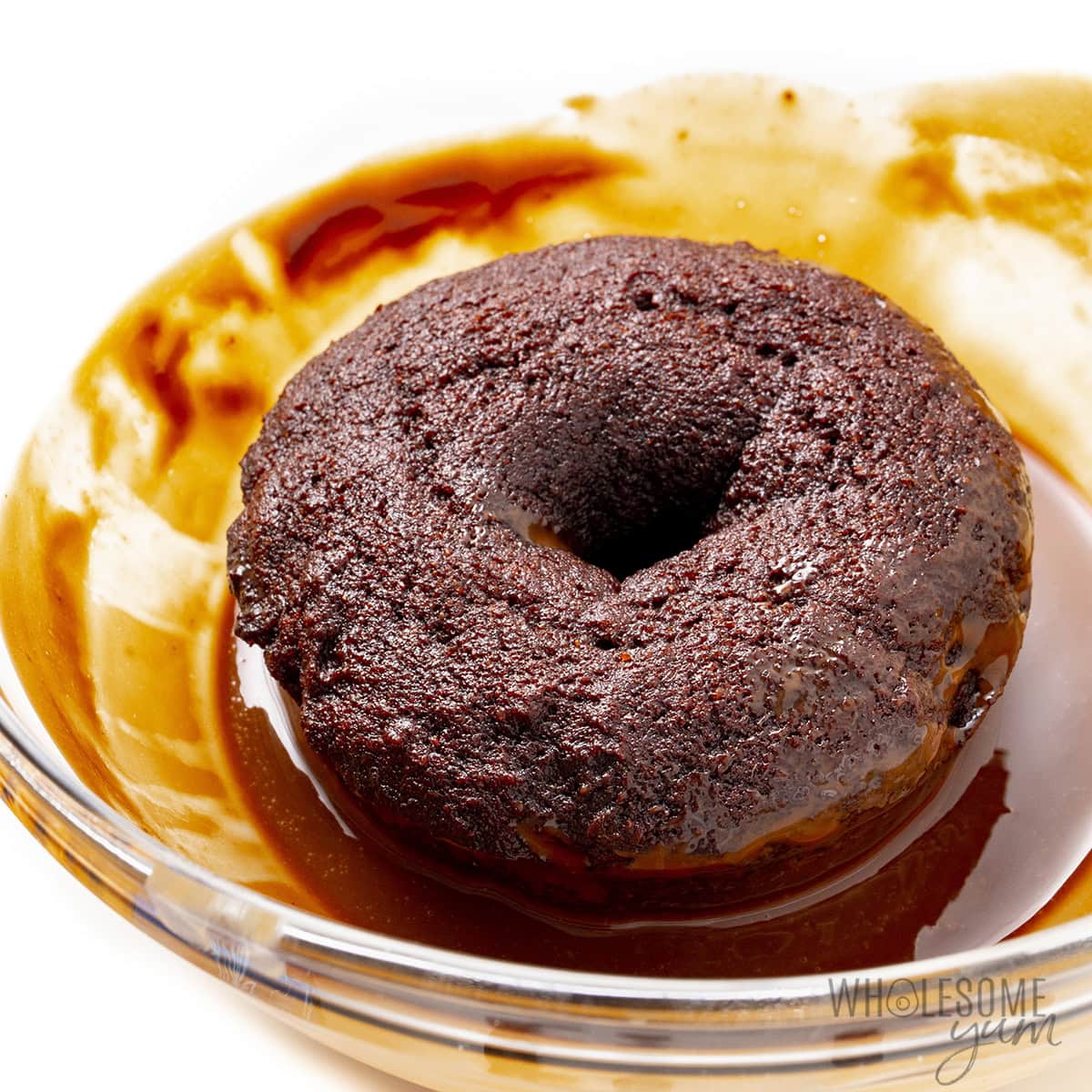 Coating a donut in chocolate glaze.