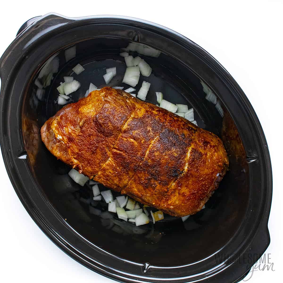 Seared pork in crock pot with onions.