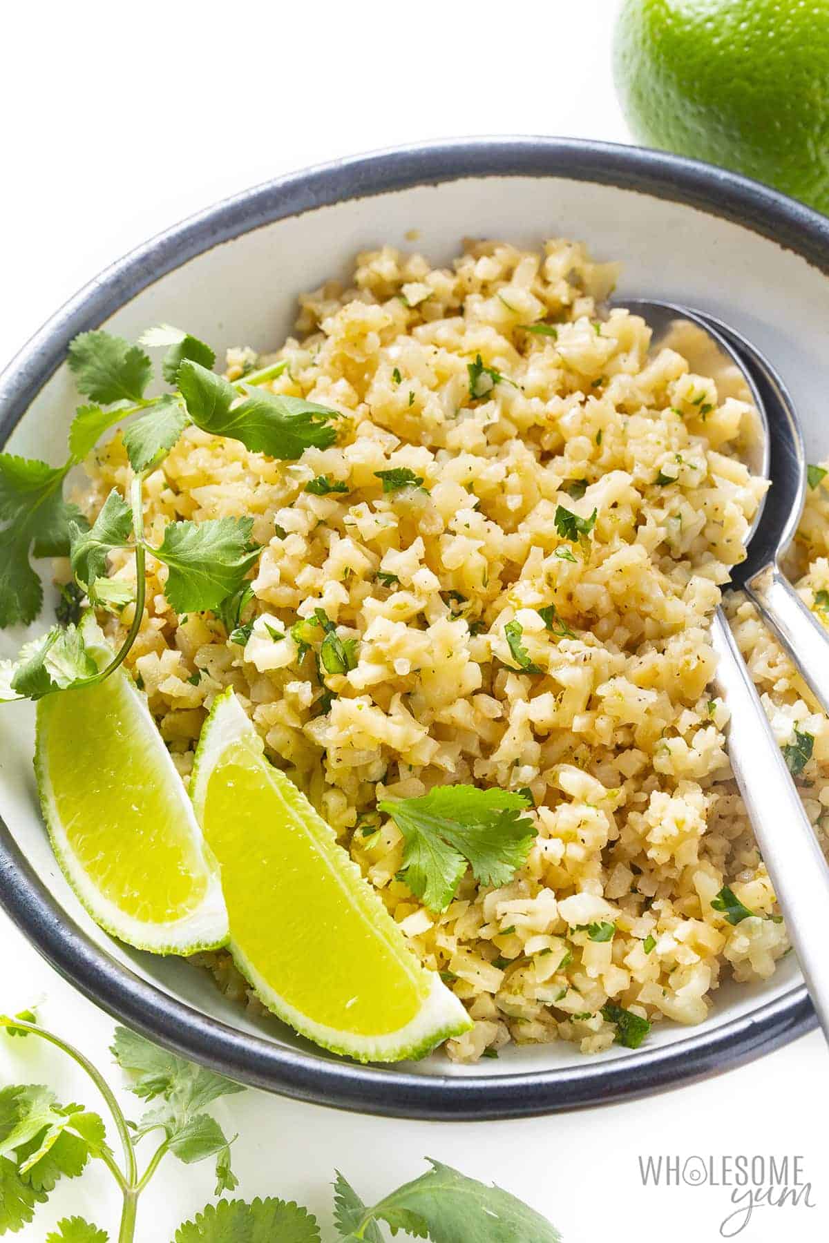 Cilantro lime cauliflower rice in a bowl with lime wedges