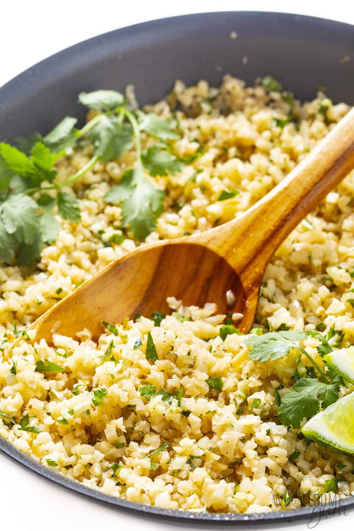 Cilantro lime cauliflower rice in a pan with wooden spoon