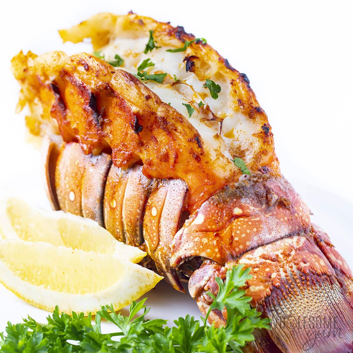 Finished lobster tail recipe with parsley and lemon.