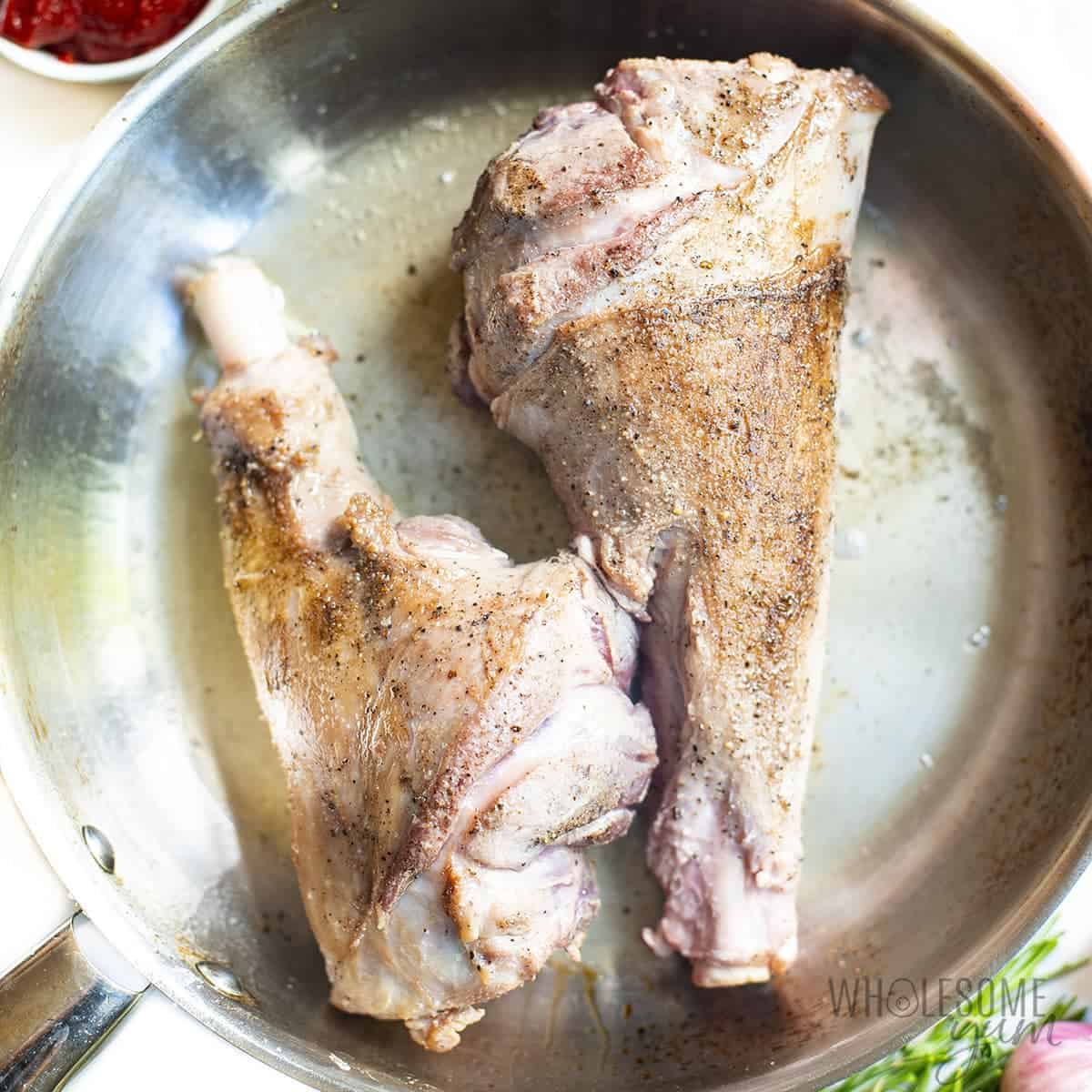 Seared lamb shanks in a skillet