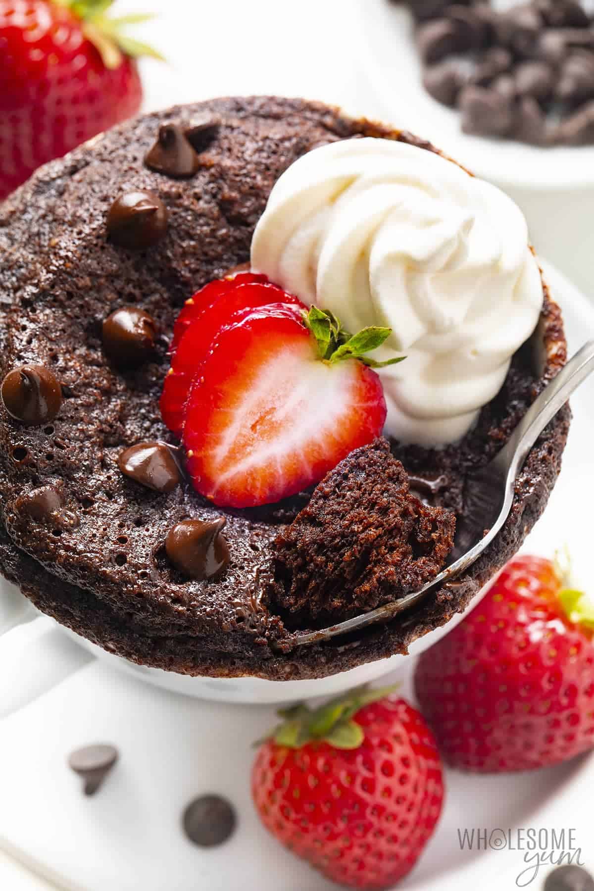 Mug cake garnished with strawberries and whipped cream