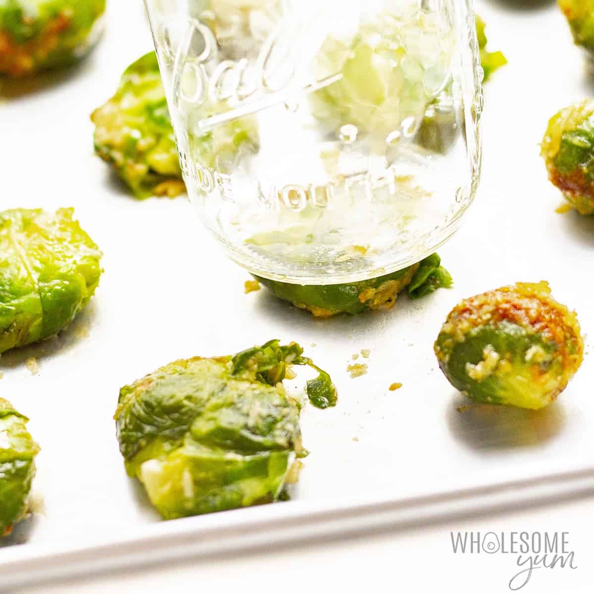 Brussels sprouts smashed under a glass mason jar