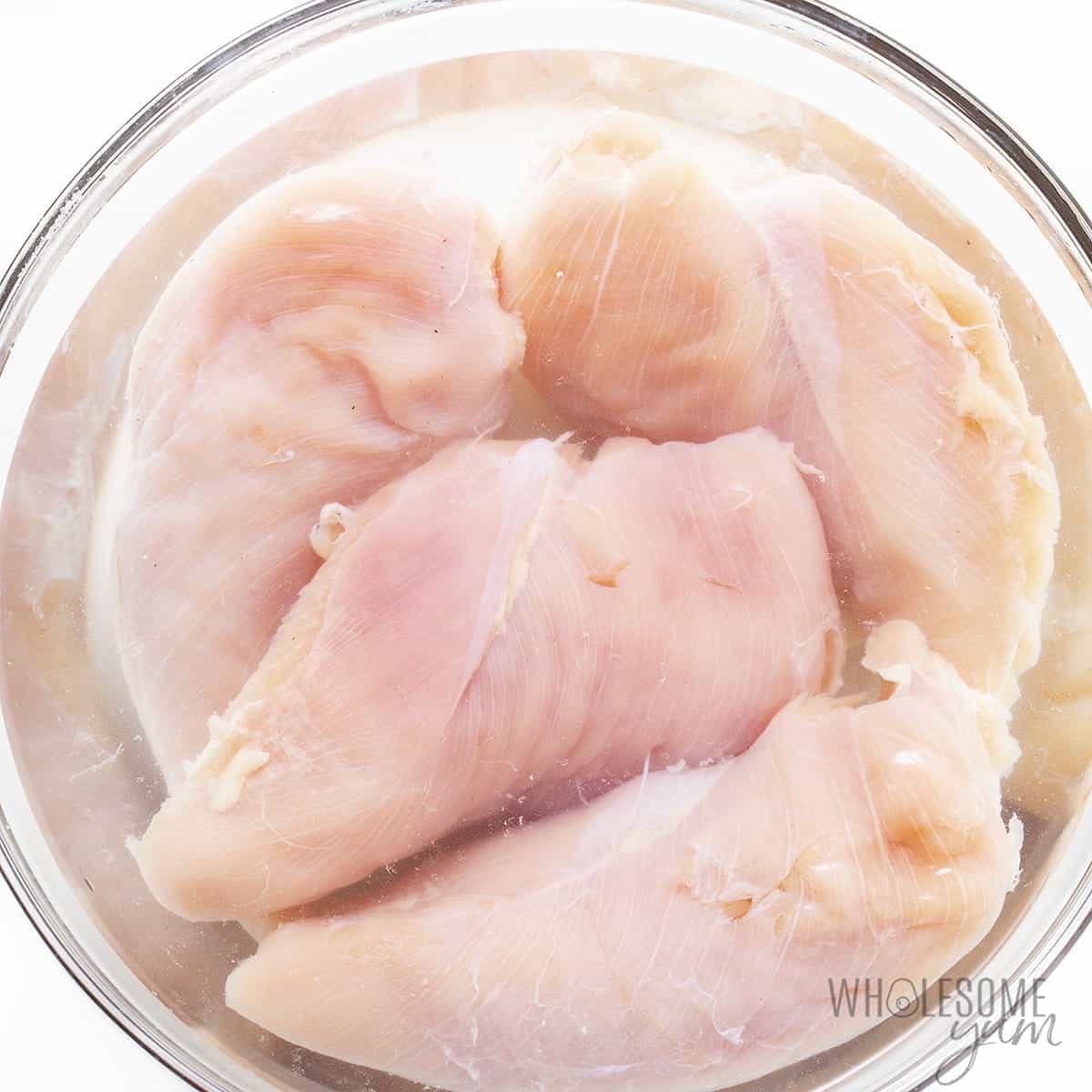 Brining chicken breast in glass bowl