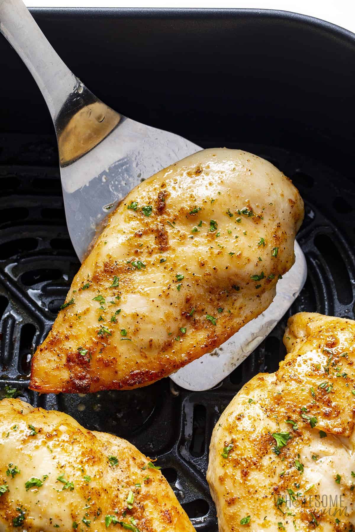 Cooked chicken breast in air fryer with serving spatula