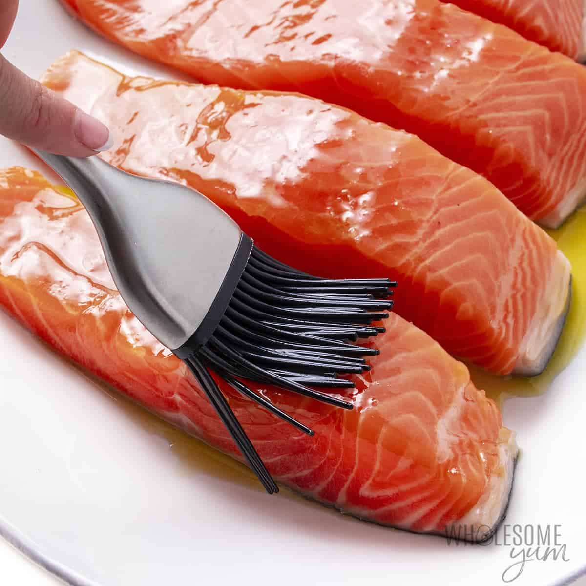 Brushing olive oil over salmon fillets