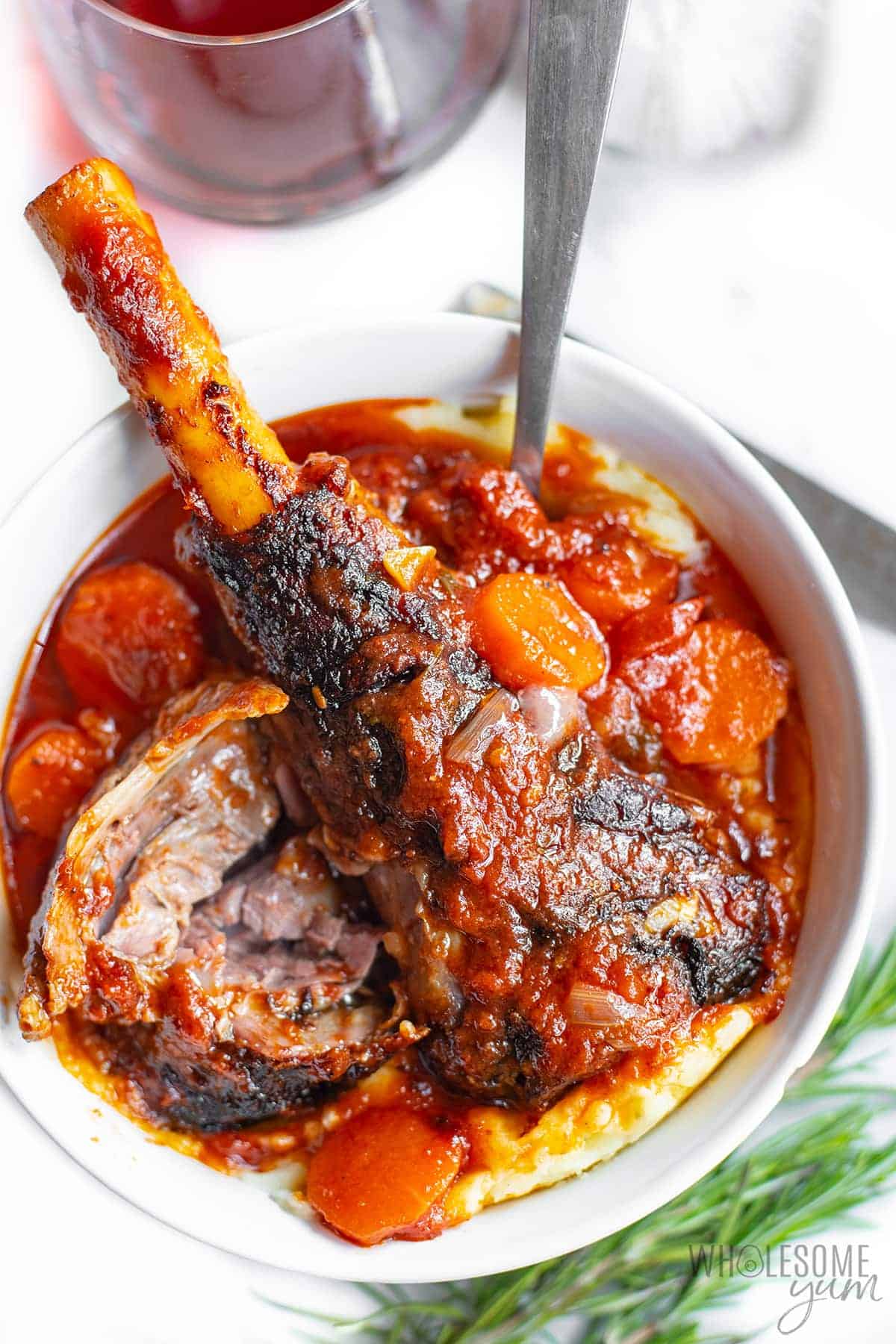 Lamb shanks in a bowl with mashed cauliflower and rosemary
