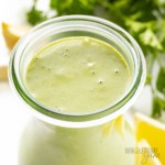Green goddess dressing recipe close up with lemons and herbs in the background.