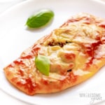 Whole low carb calzone on a plate with basil leaves