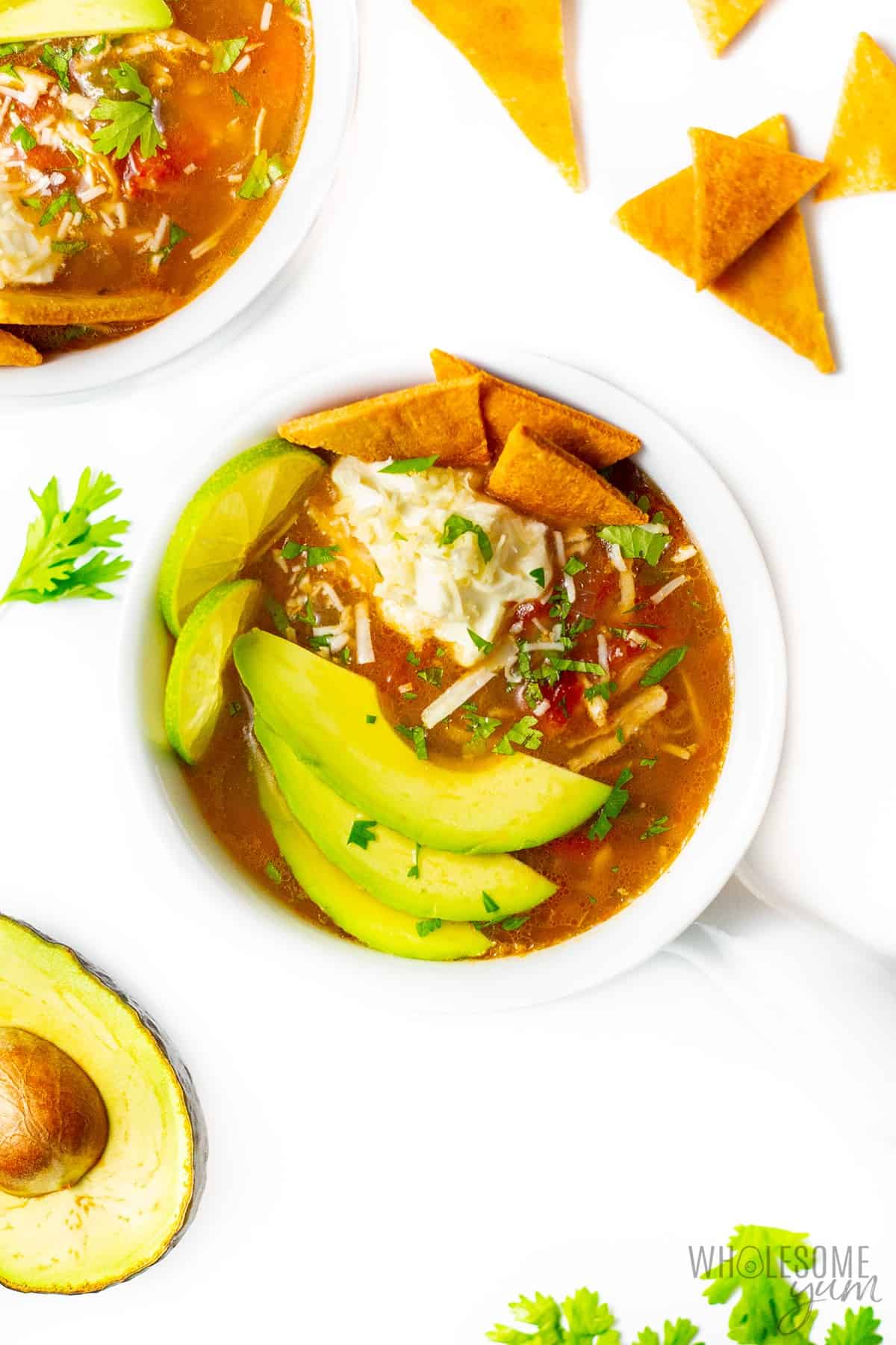Low carb chicken tortilla soup in bowls with ingredients scattered