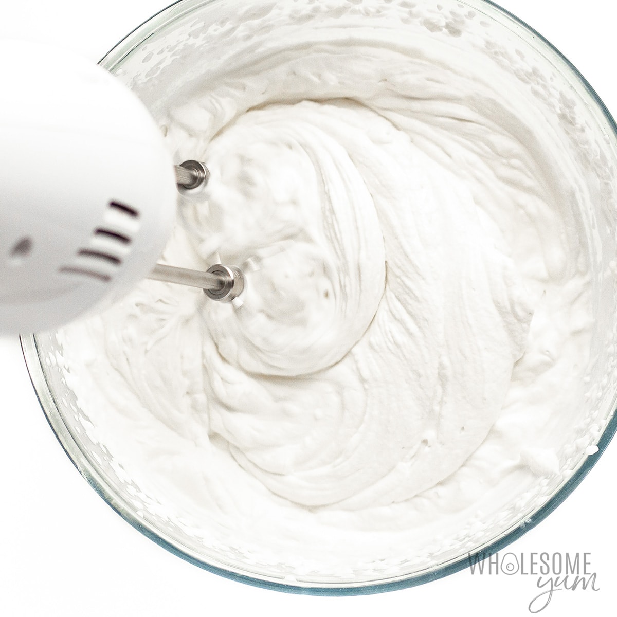 Whipping cream in a bowl with mixer.
