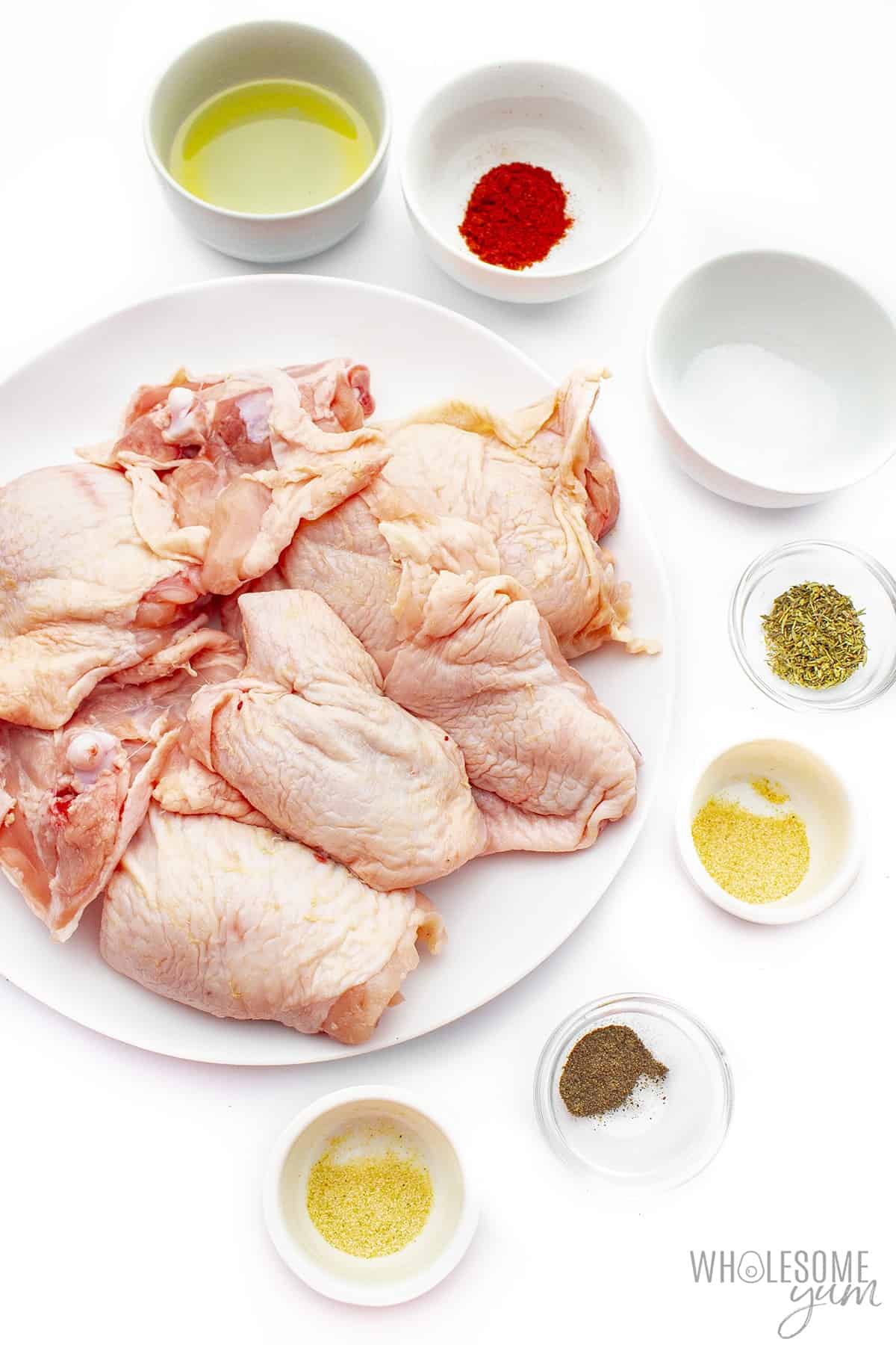 Chicken thighs and seasoning ingredients in bowls.