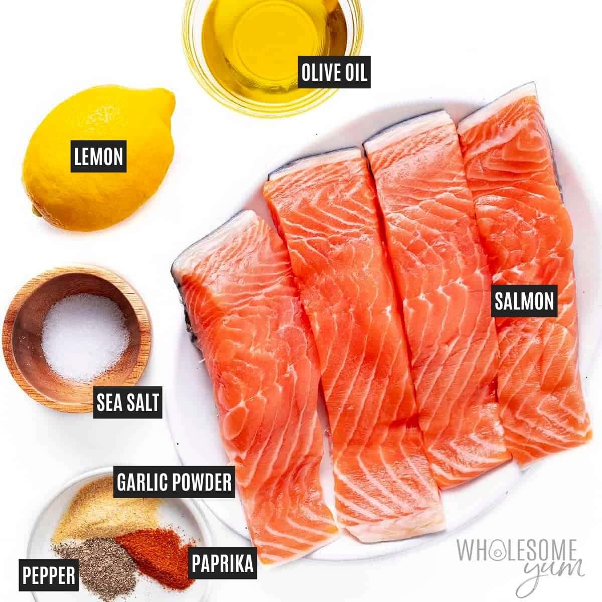 Salmon on a plate next to seasonings, olive oil, and lemon.