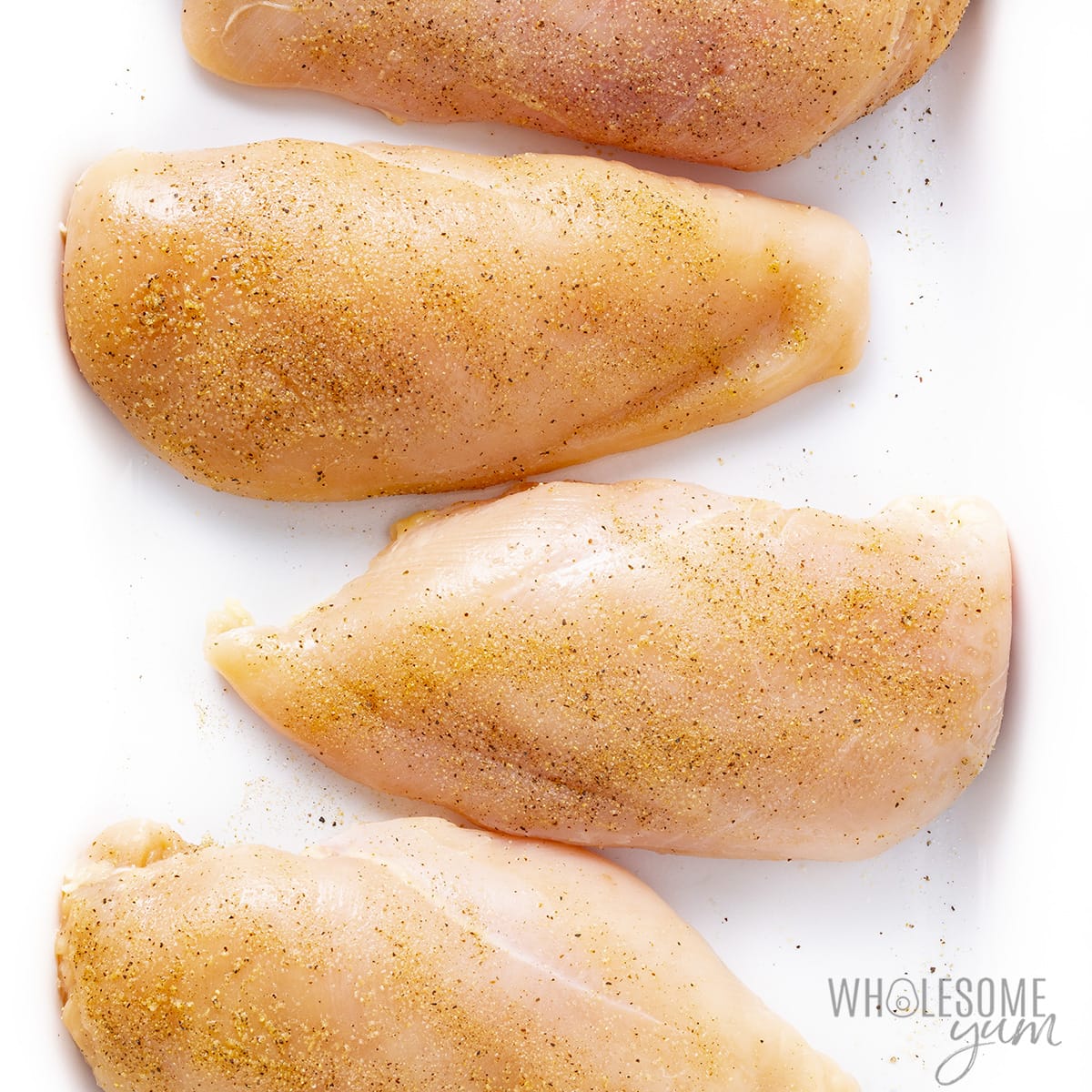 Seasoned chicken breasts in a baking dish.