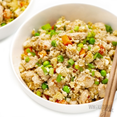 Bowl of cauliflower chicken fried rice in a bowl with chopsticks.