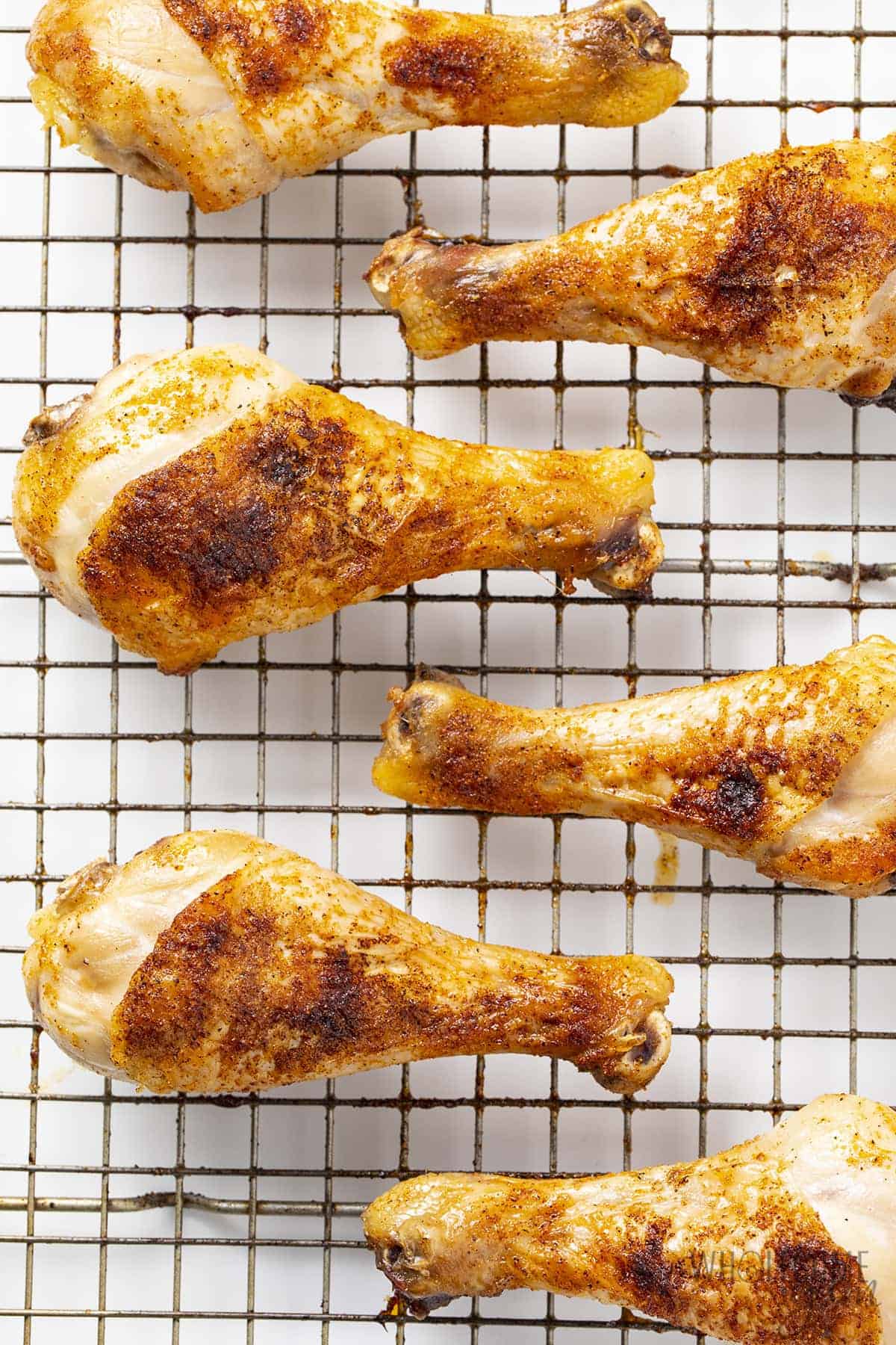 Crispy baked chicken drumsticks in the oven on a rack.