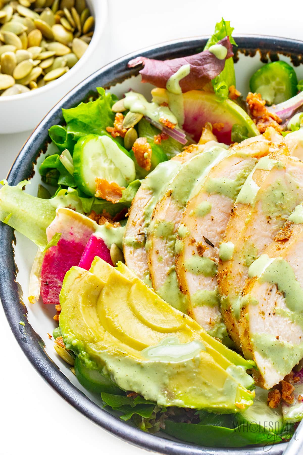Green goddess salad in a bowl with dressing drizzled on top