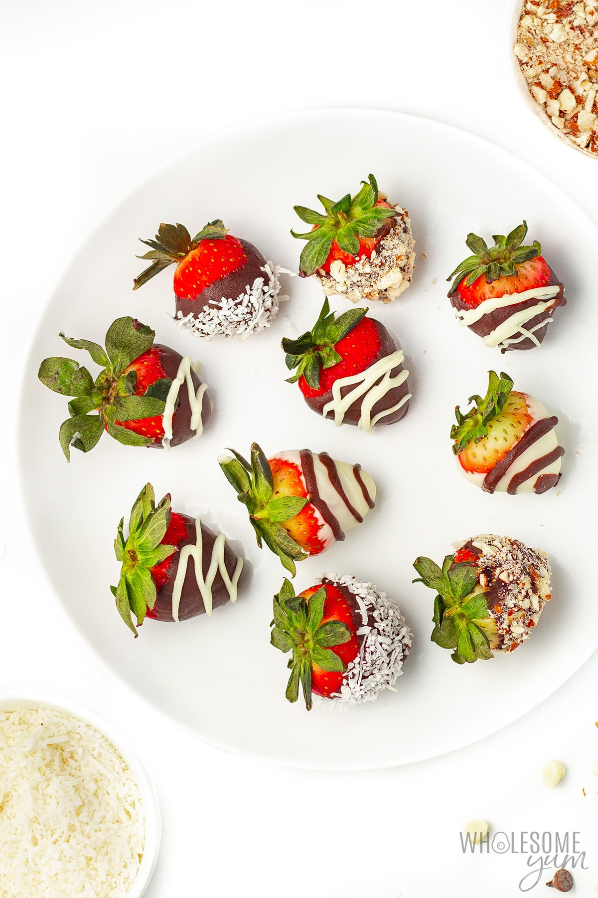 Low carb chocolate covered strawberries with nuts and coconut garnishes.