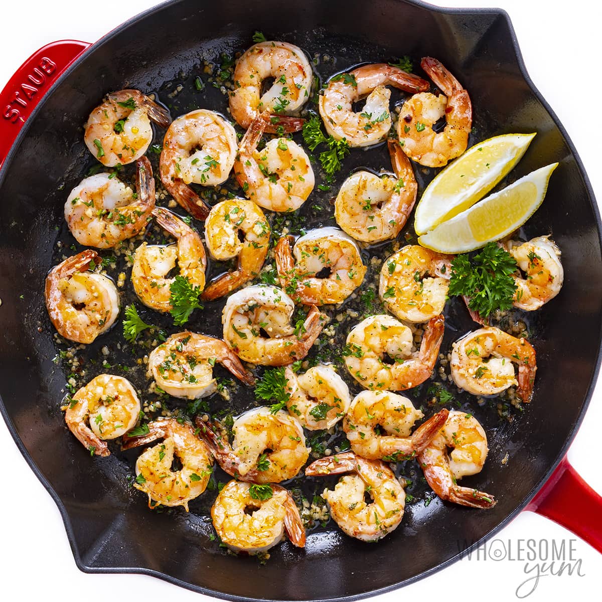Cooked garlic butter shrimp recipe in a skillet with lemon wedges.