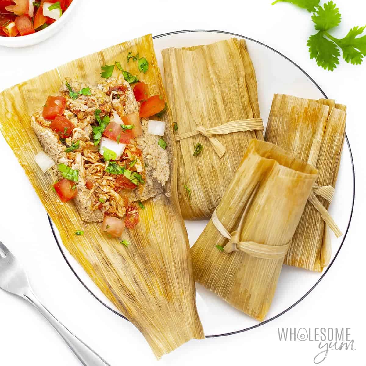 Keto tamales on a plate, one unwrapped.