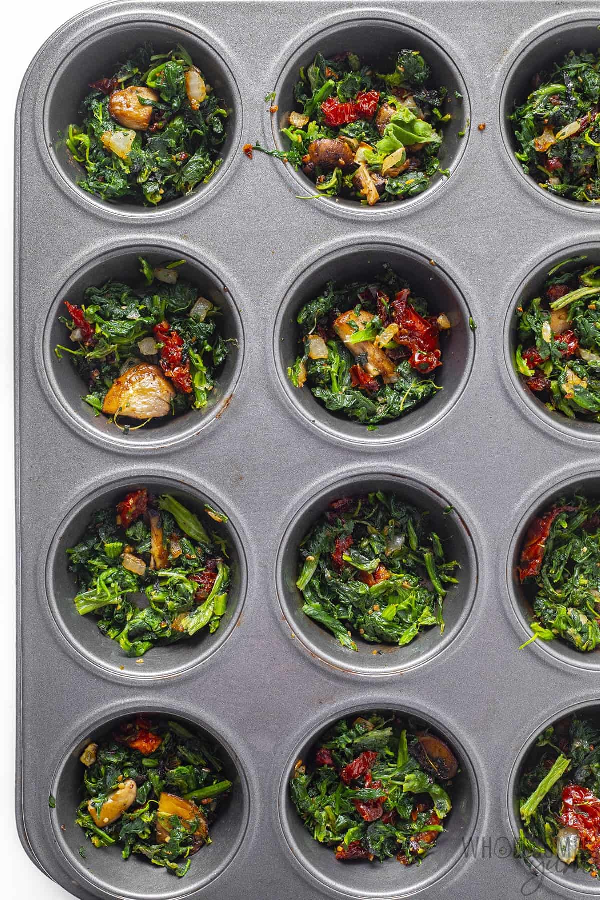 Cooked vegetables in muffin tin.