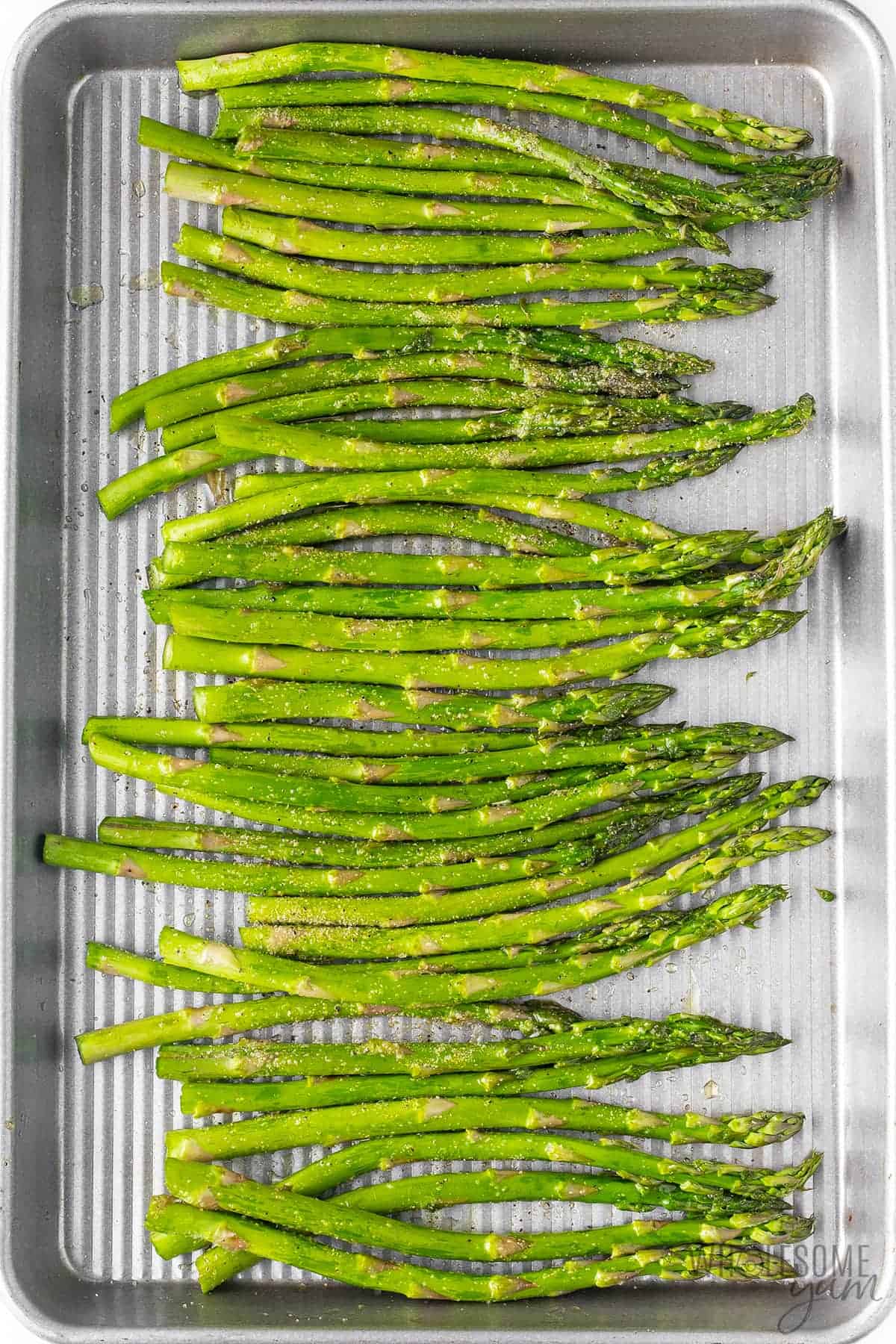 Seasoned asparagus on a sheet pan.