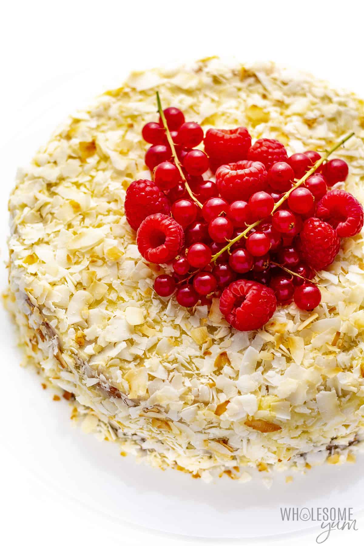 Full coconut flour cake topped with red berries.
