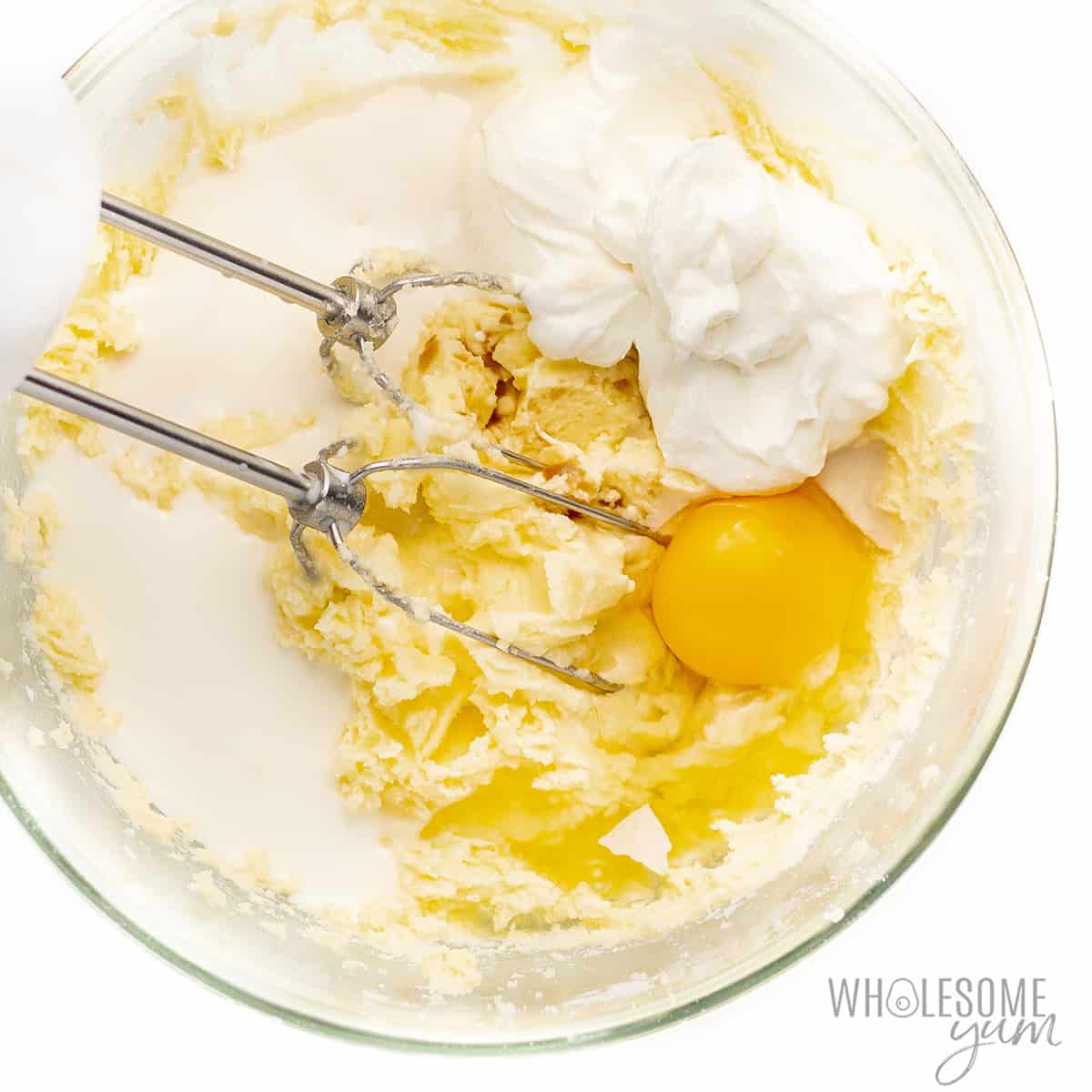 Wet ingredients added to butter and sweetener mixture in a bowl.