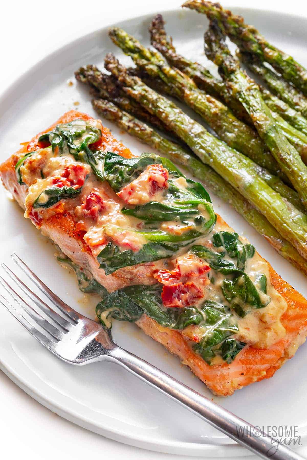 Creamy Tuscan salmon plated with sun-dried tomatoes and spinach.